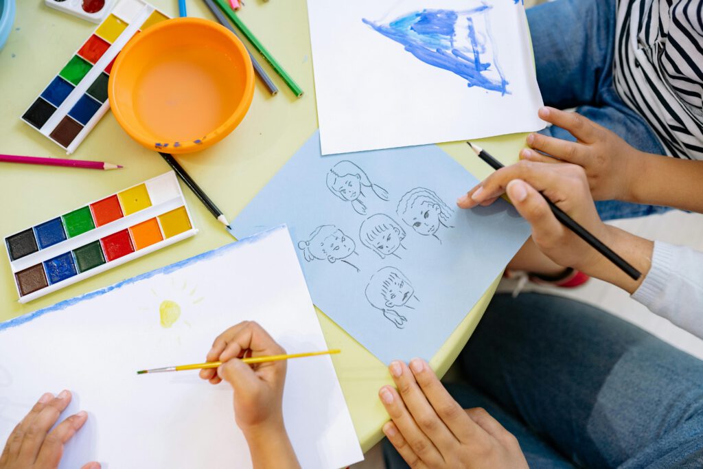 Young children engaging in a colorful art session with paints and drawings.